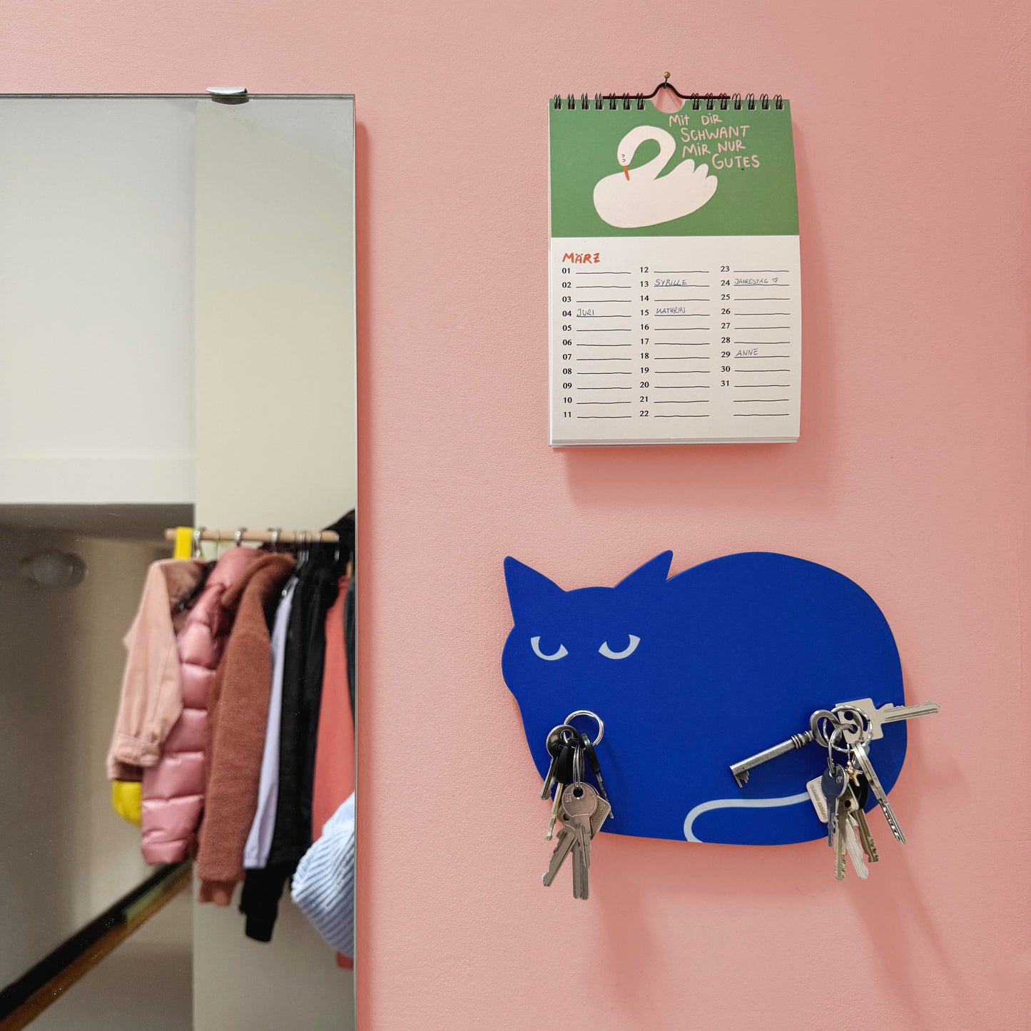 a magnetic key holder shaped like a cat in the color blue hanging on the wall in a entrance area