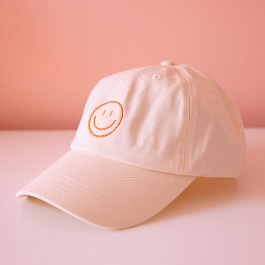 Seitenansicht beige Cap mit aufgesticktem orangem Smiley