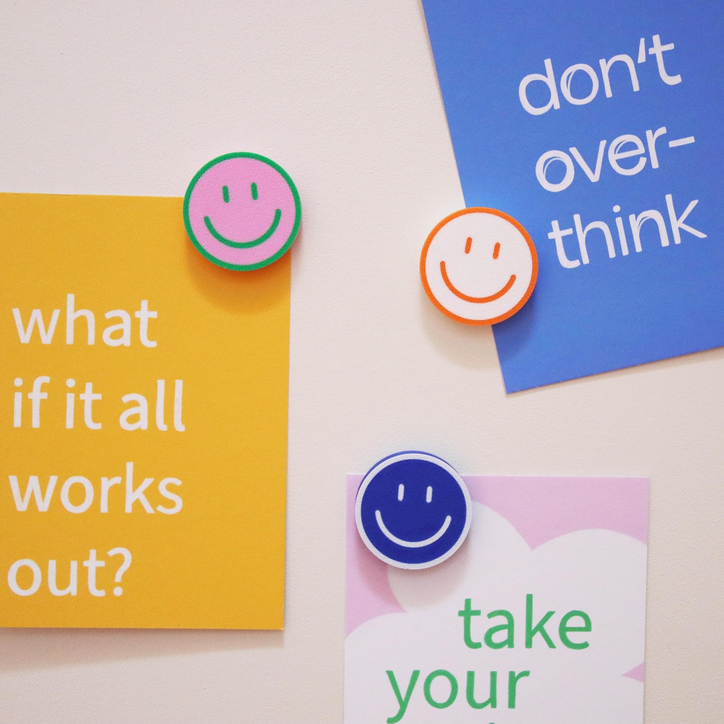 colorful 3D-printed smiley magnets holding colorful postcards