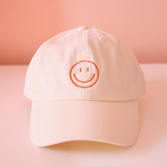 Frontansicht beige Cap mit aufgesticktem orangem Smiley