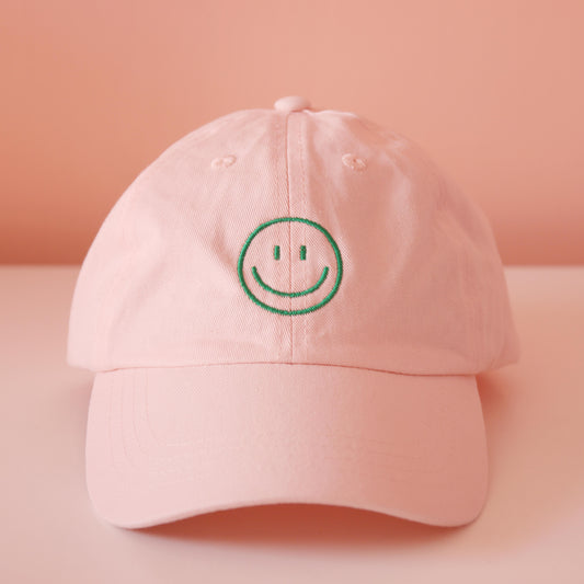 Frontansicht rosa Cap mit aufgesticktem grünem Smiley