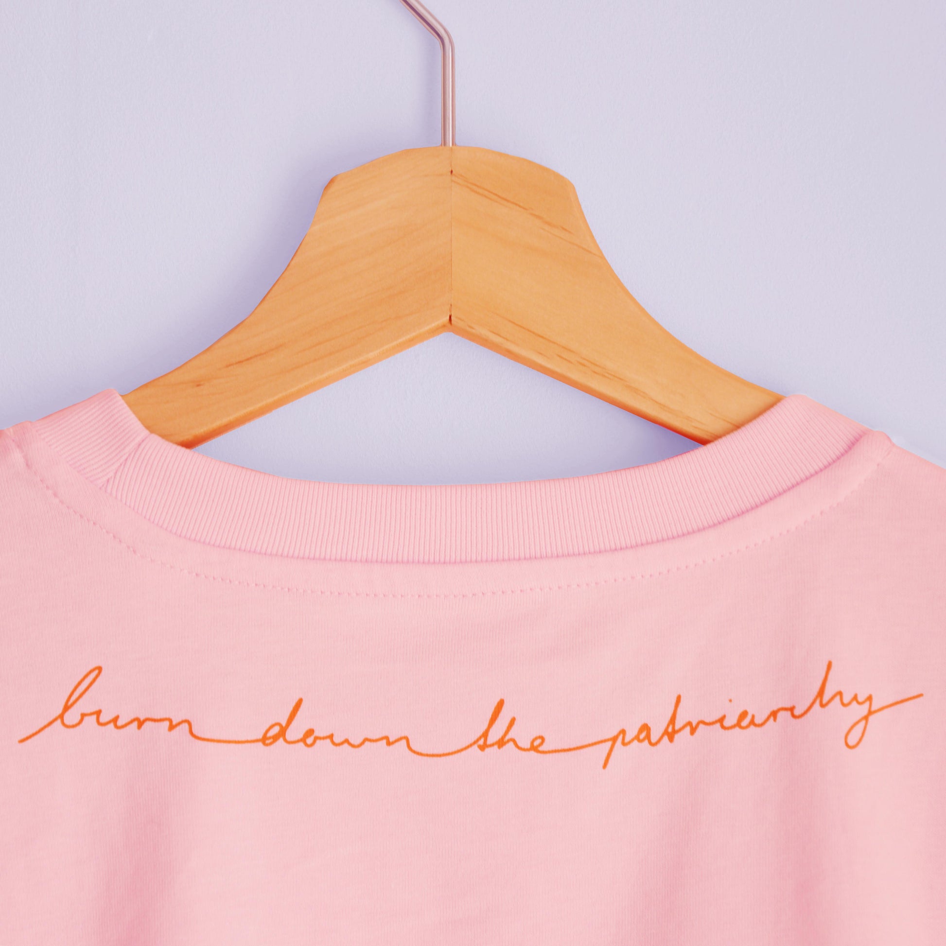 Rückenansicht rosa T-Shirt mit dem Spruch "Burn Down The Patriarchy" in geschwungener Schreibschrift m Nacken